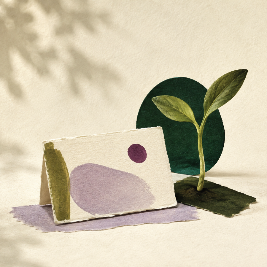 Cut-paper still life of a sprout beside a blank name card.
